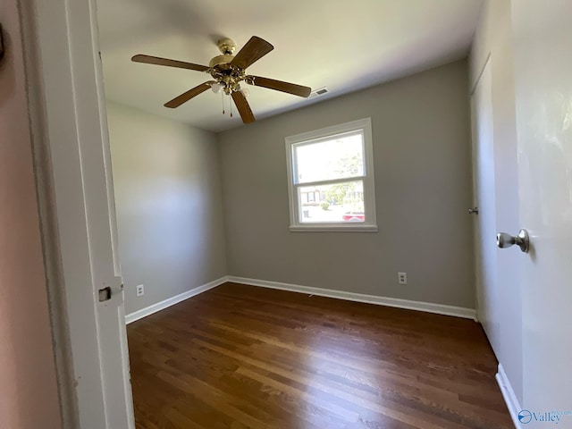 unfurnished room with dark wood-type flooring, baseboards, a ceiling fan, and visible vents