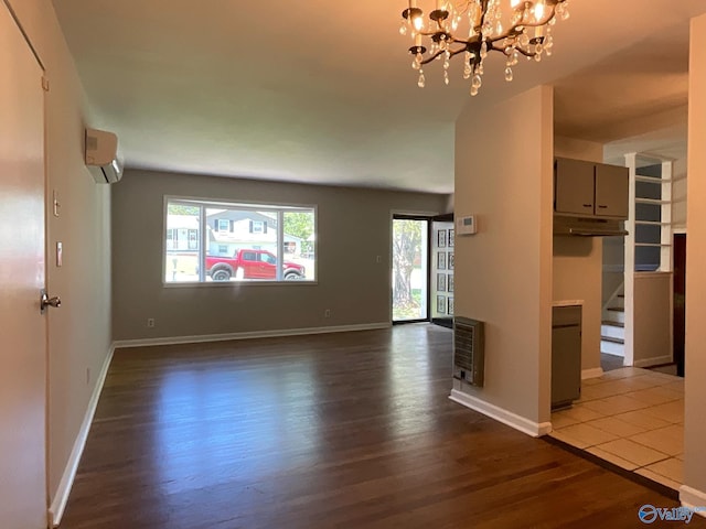 unfurnished living room featuring baseboards, a wall mounted air conditioner, dark wood-style flooring, heating unit, and a chandelier