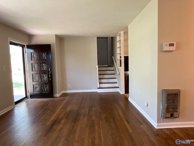 interior space with stairs, baseboards, heating unit, and wood finished floors