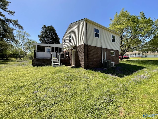 back of property featuring a yard, a wooden deck, brick siding, and central air condition unit
