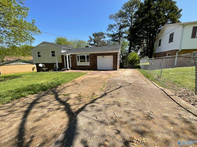 split level home featuring concrete driveway, a front lawn, entry steps, a garage, and fence