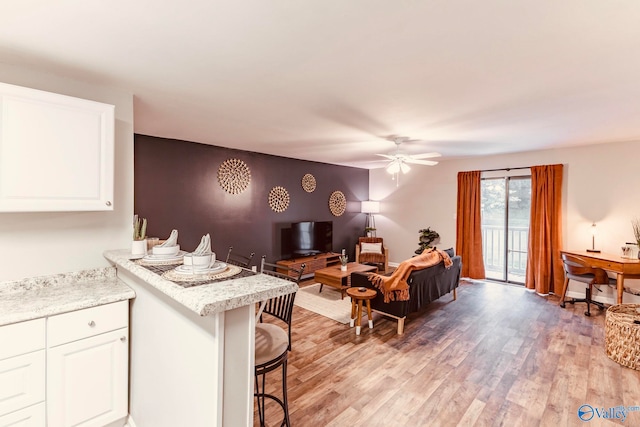 interior space featuring white cabinetry, a breakfast bar, light hardwood / wood-style flooring, and ceiling fan