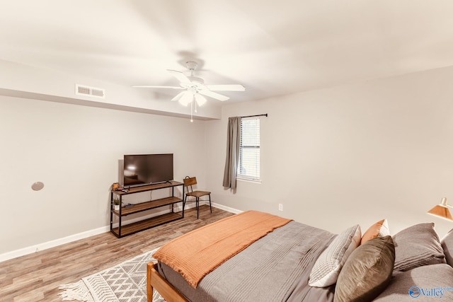 bedroom with a ceiling fan, light wood-style flooring, visible vents, and baseboards