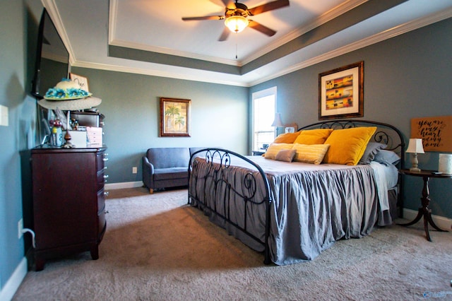 carpeted bedroom with ceiling fan, a raised ceiling, and ornamental molding