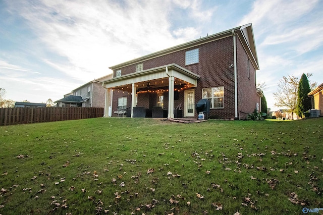 rear view of property featuring a lawn, ceiling fan, and central AC unit