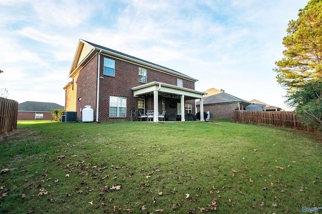 back of property with central AC and a lawn