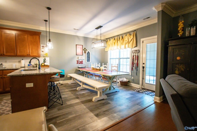 dining area featuring dark hardwood / wood-style flooring, ornamental molding, and sink