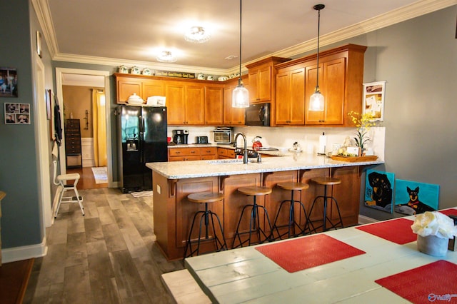 kitchen featuring black appliances, dark hardwood / wood-style floors, ornamental molding, and hanging light fixtures