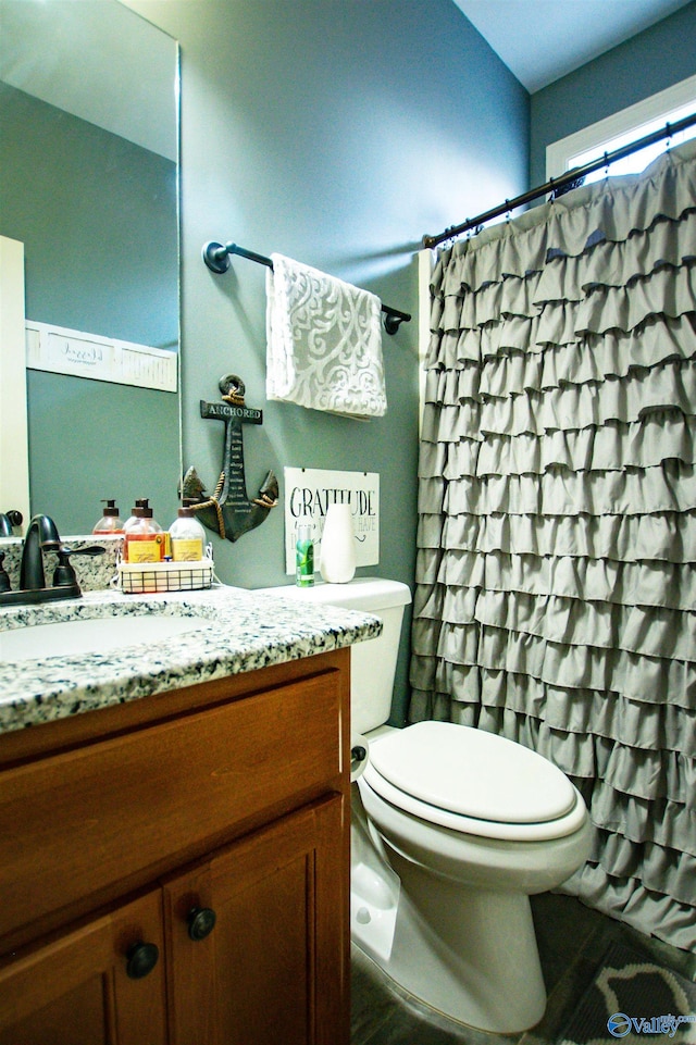 bathroom featuring vanity, curtained shower, and toilet