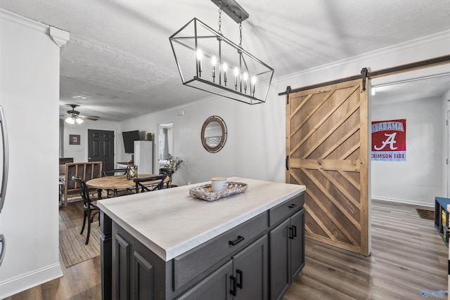 kitchen with a textured ceiling, hanging light fixtures, a center island, a barn door, and ceiling fan