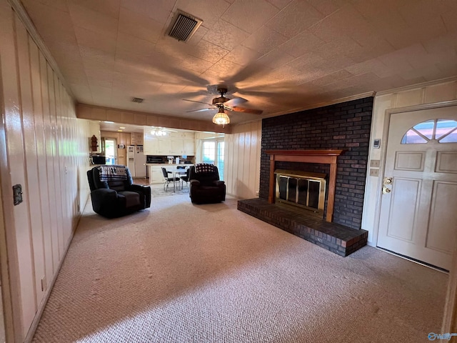 unfurnished living room featuring ceiling fan, brick wall, a brick fireplace, and light colored carpet