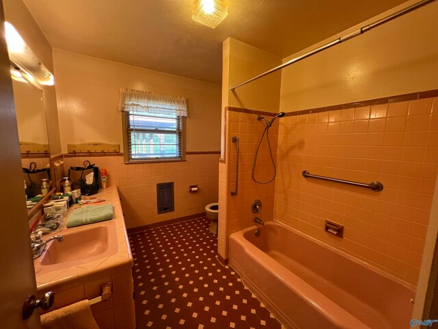 full bathroom featuring vanity, tiled shower / bath, toilet, a textured ceiling, and tile patterned flooring