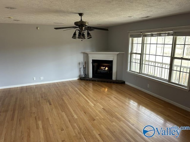 unfurnished living room with ceiling fan, wood-type flooring, and a textured ceiling