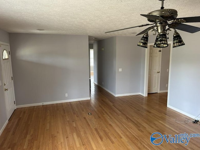 empty room featuring ceiling fan, wood-type flooring, and a textured ceiling