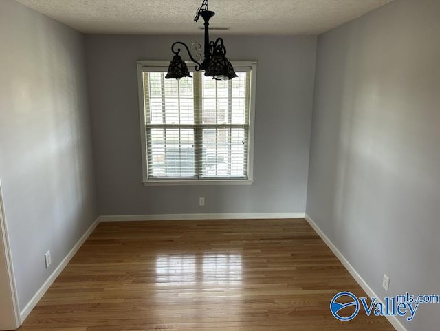 unfurnished dining area with a textured ceiling and hardwood / wood-style floors