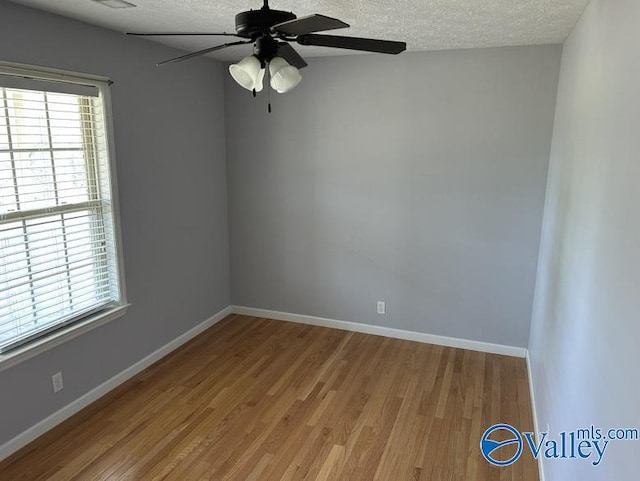 unfurnished room featuring a textured ceiling, light wood-type flooring, and a wealth of natural light