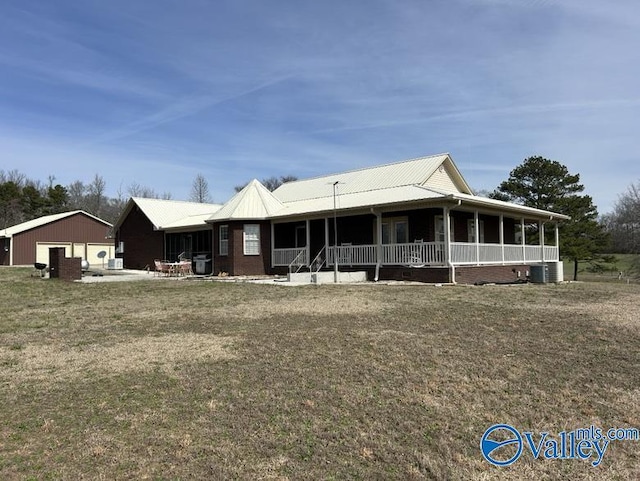 view of front of property featuring a garage, central air condition unit, a front lawn, and a porch