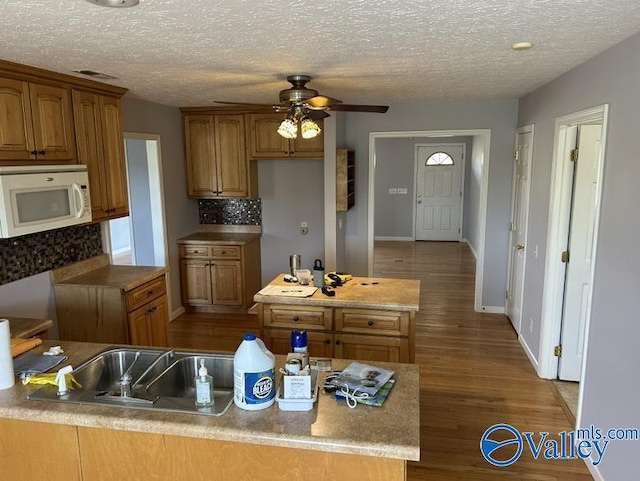 kitchen with ceiling fan, tasteful backsplash, a textured ceiling, and hardwood / wood-style floors