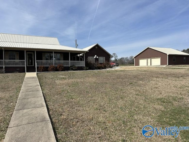 view of front of house featuring a garage, an outbuilding, a front yard, and a porch