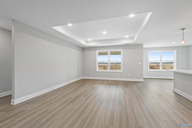 unfurnished living room featuring light hardwood / wood-style floors and a tray ceiling