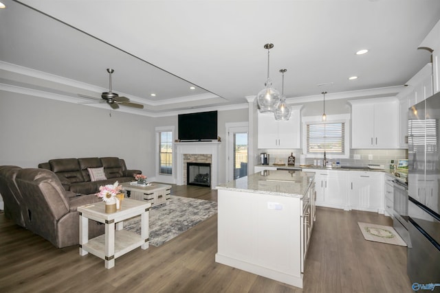 kitchen with a kitchen island, white cabinetry, light stone countertops, dark hardwood / wood-style floors, and decorative light fixtures