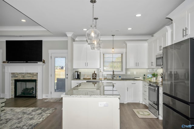 kitchen featuring a center island, light stone counters, stainless steel appliances, and white cabinetry