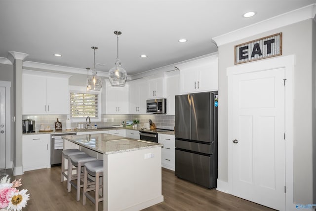 kitchen with appliances with stainless steel finishes, dark wood-type flooring, hanging light fixtures, and a kitchen island