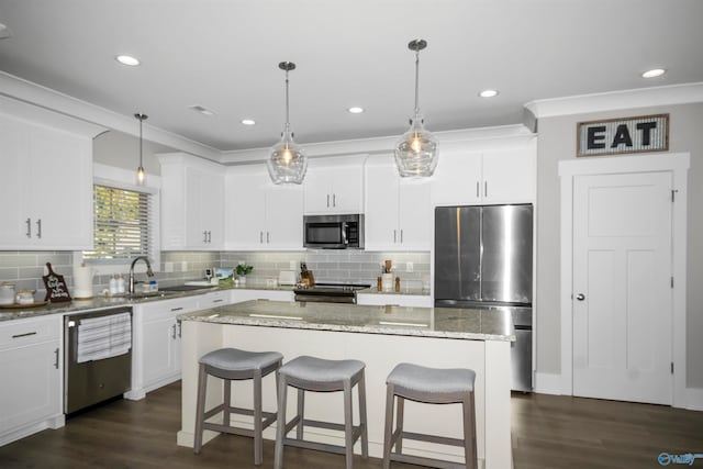 kitchen featuring dark hardwood / wood-style floors, stainless steel appliances, decorative light fixtures, and a kitchen island