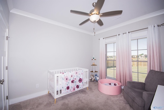 bedroom featuring ornamental molding, a nursery area, carpet floors, and ceiling fan