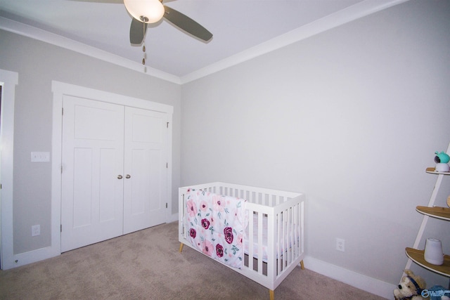 bedroom featuring a closet, light colored carpet, a crib, and ceiling fan