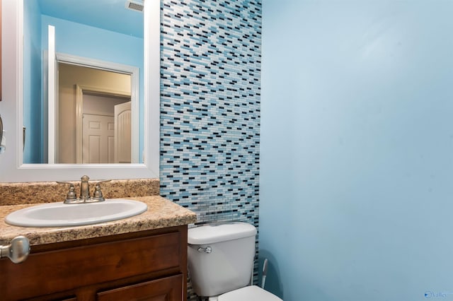 bathroom featuring vanity, toilet, and backsplash