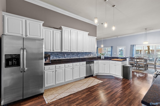 kitchen with dark wood-type flooring, a sink, dark countertops, appliances with stainless steel finishes, and a peninsula