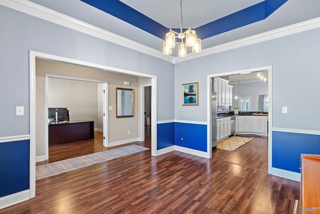 empty room featuring a raised ceiling, dark wood-style floors, an inviting chandelier, crown molding, and baseboards