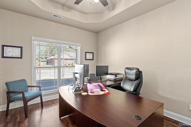 office featuring visible vents, a ceiling fan, dark wood finished floors, baseboards, and a raised ceiling