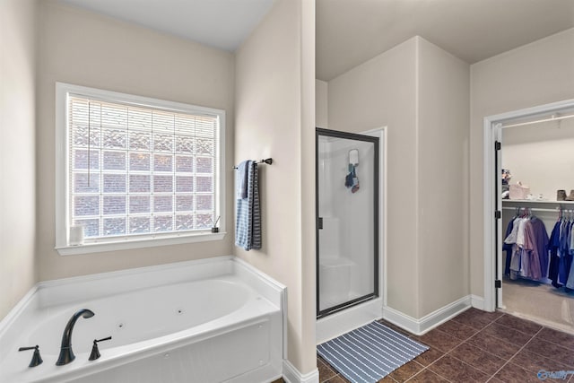 full bath with a walk in closet, a whirlpool tub, a shower stall, and tile patterned flooring