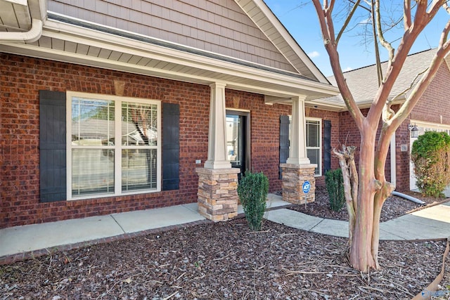 entrance to property featuring brick siding and covered porch