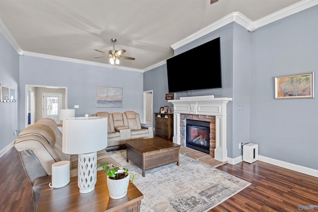 living area featuring baseboards, a stone fireplace, ceiling fan, and ornamental molding