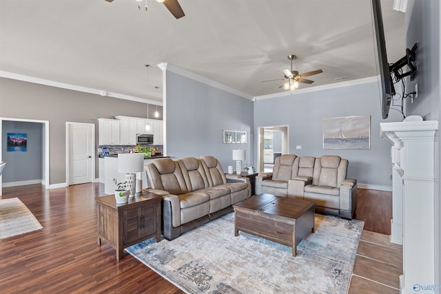 living area featuring baseboards, dark wood-type flooring, ornamental molding, and a ceiling fan