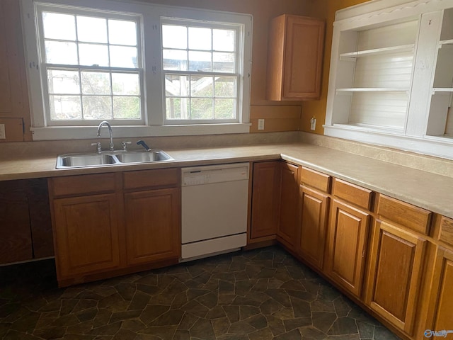 kitchen featuring light countertops, brown cabinetry, stone finish flooring, white dishwasher, and a sink