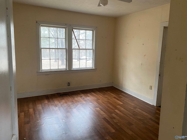 empty room with dark wood-style floors, baseboards, and a ceiling fan