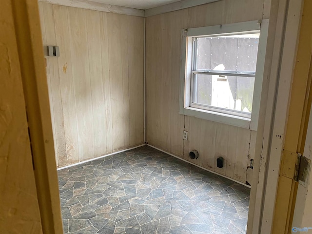 unfurnished room featuring wood walls and stone flooring