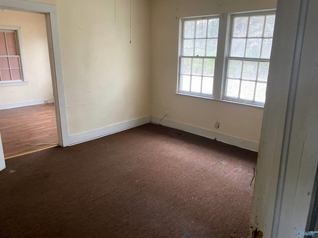 unfurnished room featuring baseboards and dark colored carpet