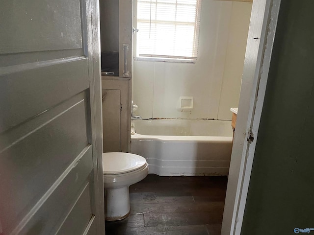 bathroom with toilet,  shower combination, and wood finished floors