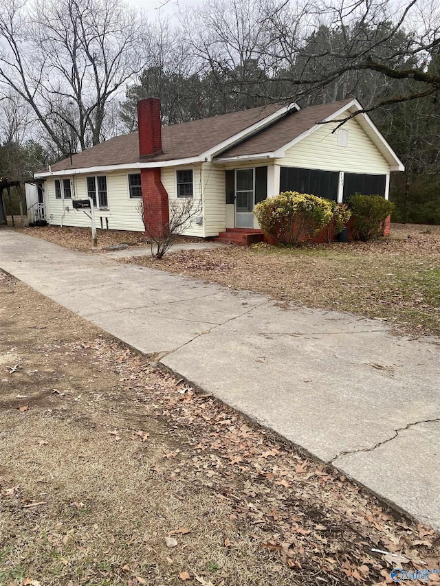 view of front facade featuring driveway and a chimney