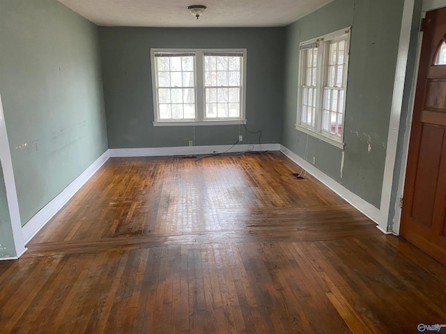 unfurnished dining area with baseboards and dark wood-type flooring