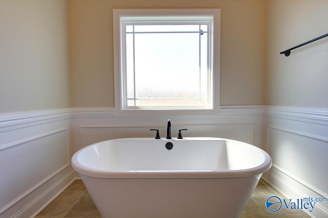 HUNTINGTONB Newby Chapel Rd, Athens, AL 35613 - full bathroom featuring a freestanding tub, healthy amount of natural light, wainscoting, tile patterned floors, and a decorative wall
