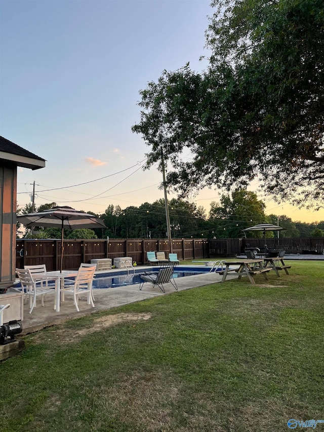 yard at dusk featuring a fenced in pool and a patio area