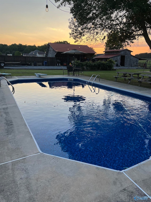 pool at dusk with a diving board and a yard