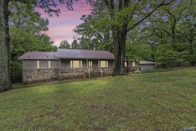 single story home featuring a porch, a front lawn, stone siding, and metal roof