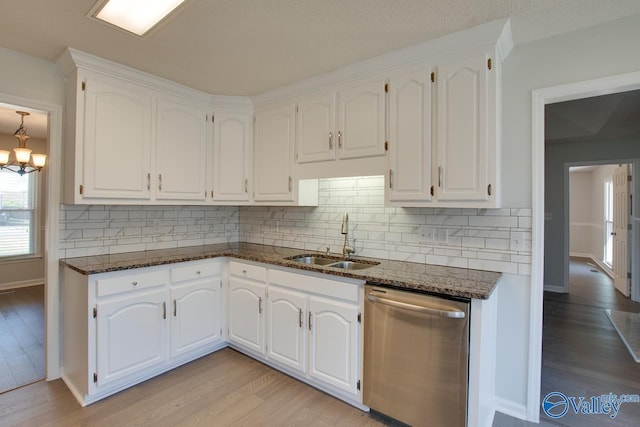 kitchen with dishwasher, white cabinetry, dark stone counters, and sink